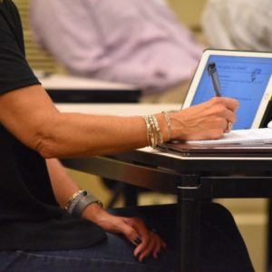 woman-taking-notes-at-a-business-conference-while-working-on-a-laptop_t20_knVxO4